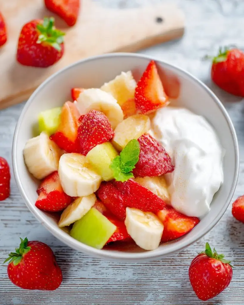 Leckere Obstsalat mit Joghurt in einer Schüssel, ideal für Frühstück oder Snack.