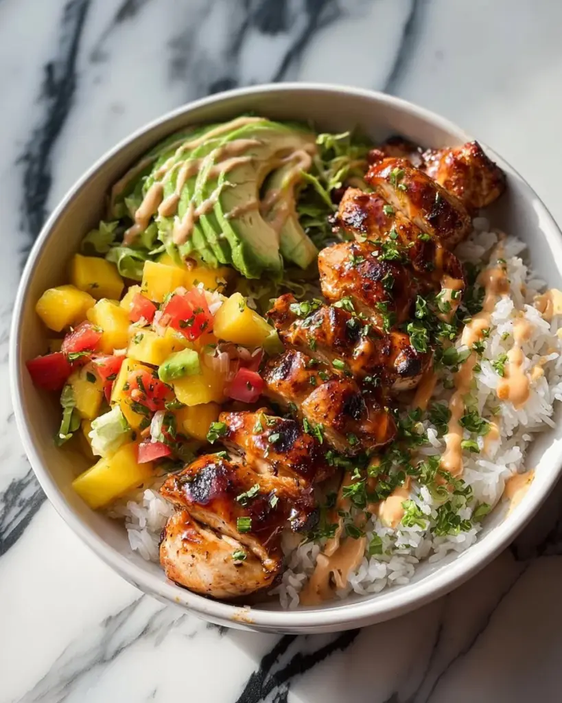Gegrillte Hühnchenstücke mit Kokosreis und Mango-Avocado-Salsa auf einem Teller